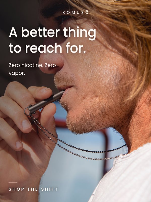 Komusō static ad: man holding a metal breathing pendant to his lips